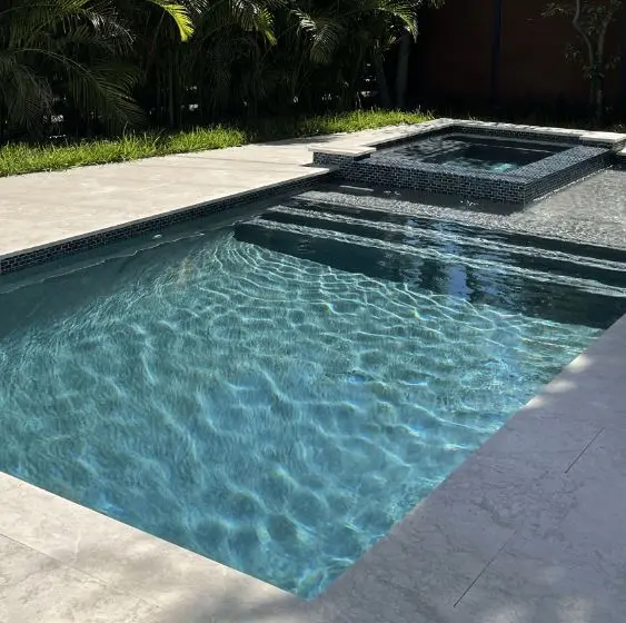Rectangular pool with dark mosaic tile and raised spa kept crystal clear with routine maintenance