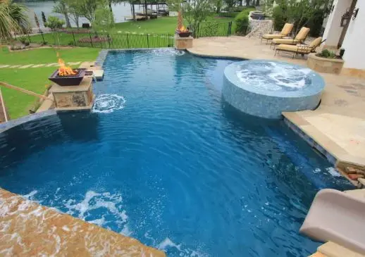 Lakefront pool with fire bowls, raised spa, and waterslide after full cleaning service