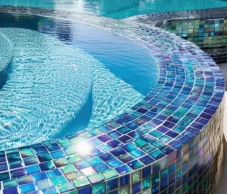 Iridescent glass mosaic tile on curved spa edge cleaned and polished by Lakeside Pool Service