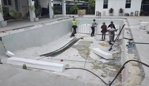 Crew working inside drained pool with rebar laid out during pool renovation project