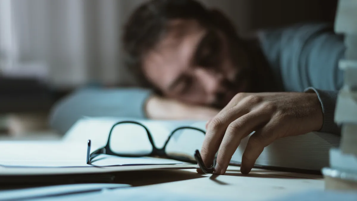 Man falling asleep at desk needing nervous system recovery and overall wellness