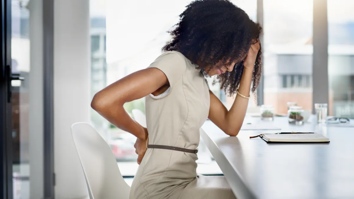 Person sitting on the edge of a bed easing out morning lower back stiffness