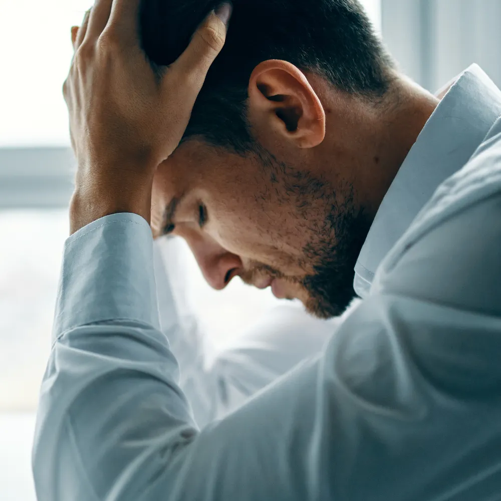 Man holding his head feeling overwhelmed and mentally stuck, representing overthinking and lack of clarity
