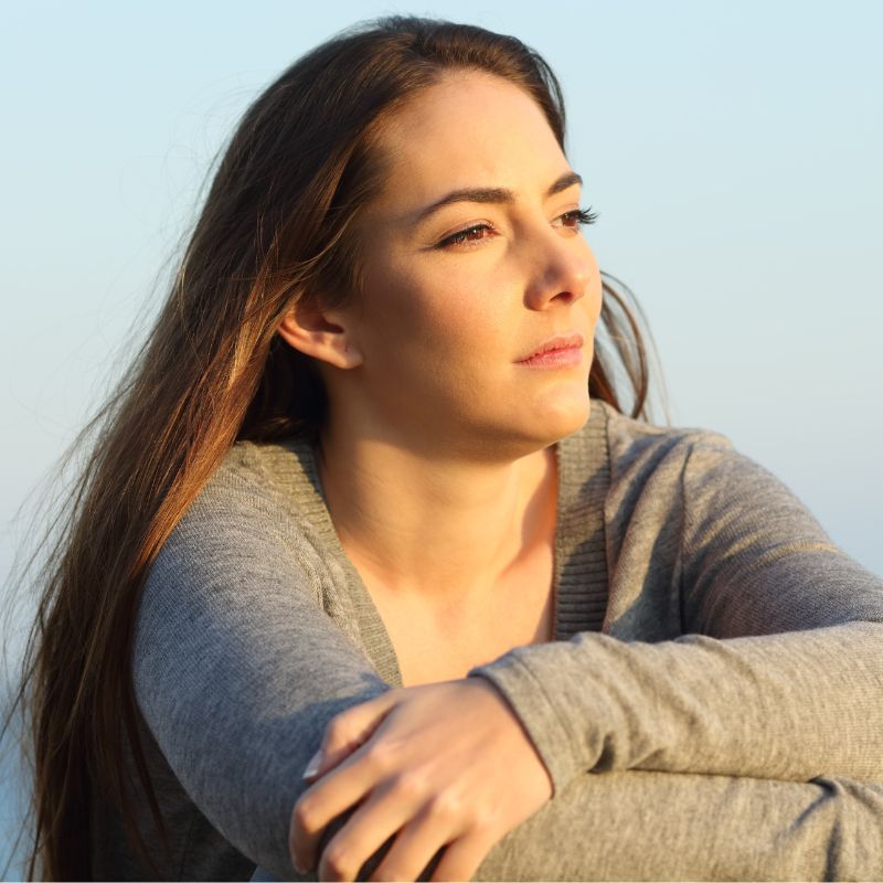 Woman looking into the distance reflecting on her life, searching for clarity and direction