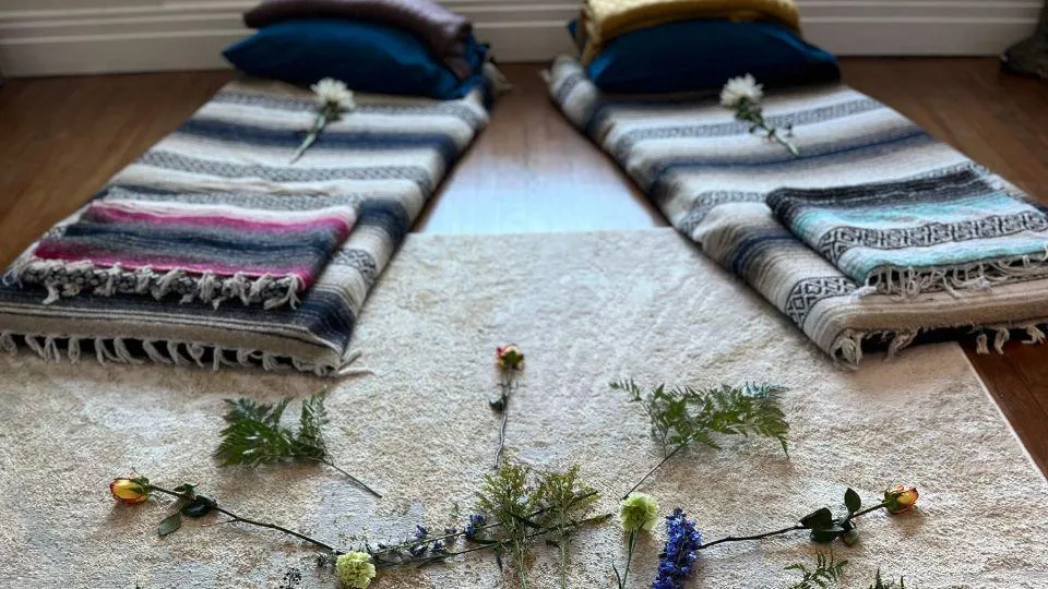 Sacred healing space with floor mats, blankets, and flowers arranged for a guided spiritual session and emotional support