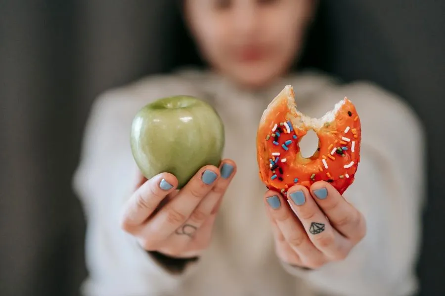 woman holding apple and doughnut