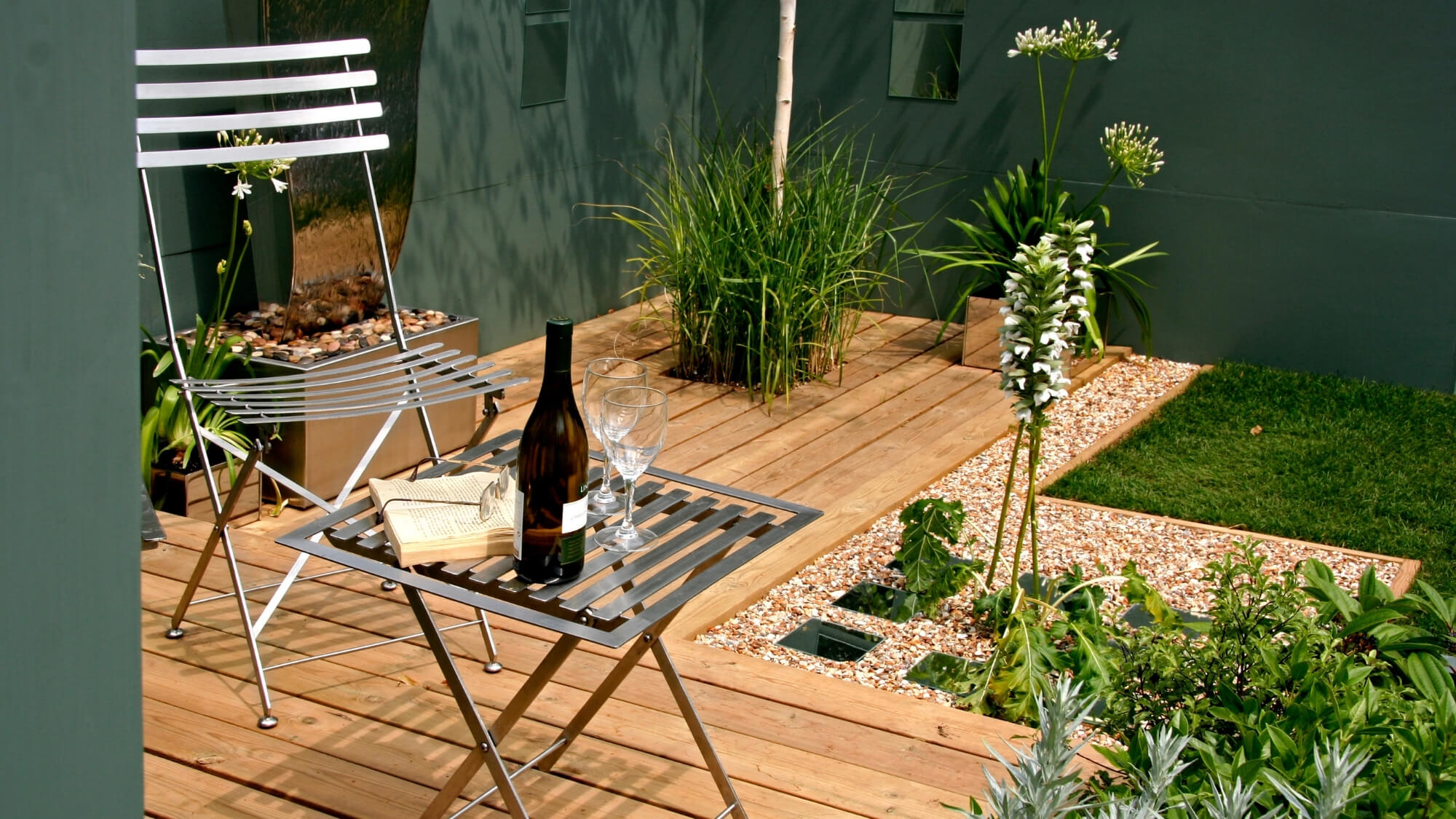 Contemporary courtyard garden with timber decking and minimalist planting in Wallington