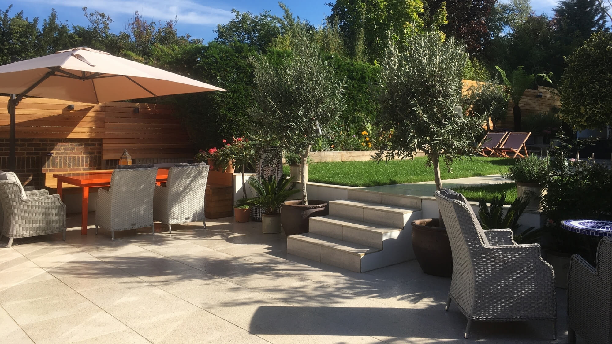 Contemporary garden design with patio, planting and outdoor seating in Surrey