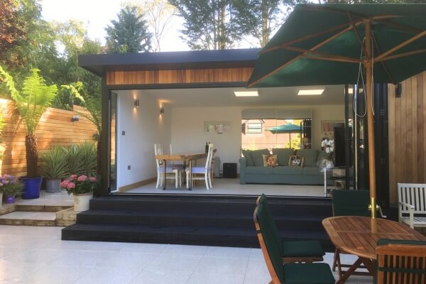 Modern garden room with decking and outdoor seating, integrated into landscaped garden
