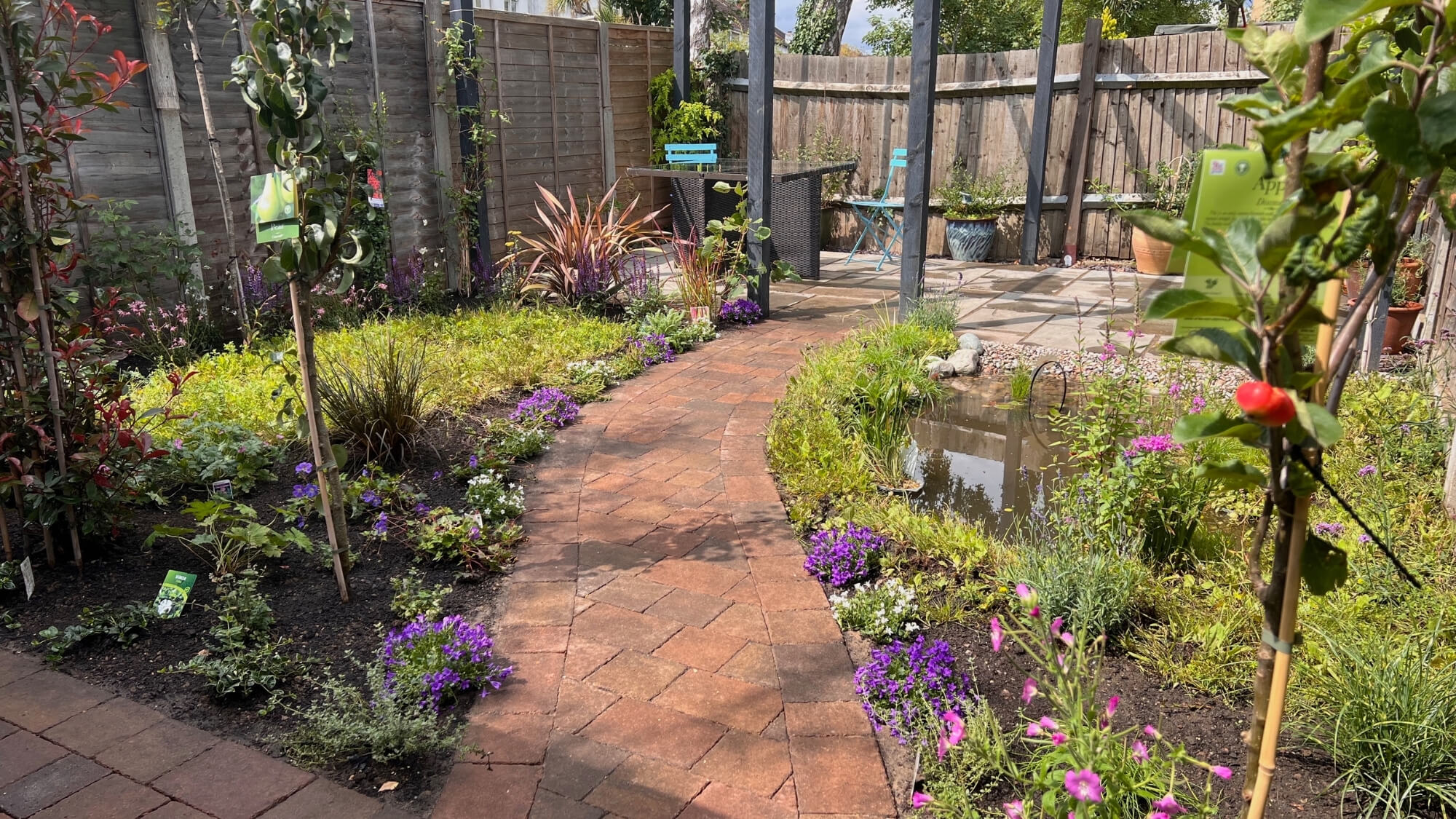 Curved stone path through wildlife planting and naturalistic pond in South Croydon garden