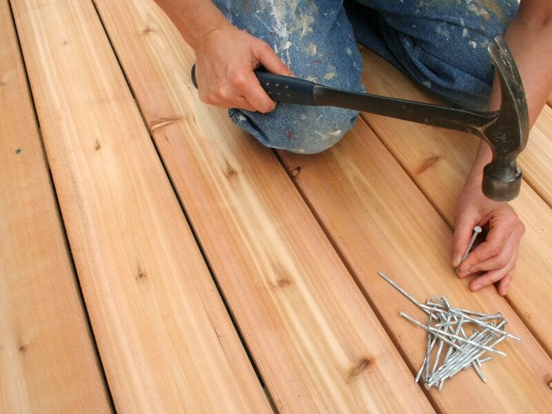Landscape gardener installing timber decking during a garden build in South London.