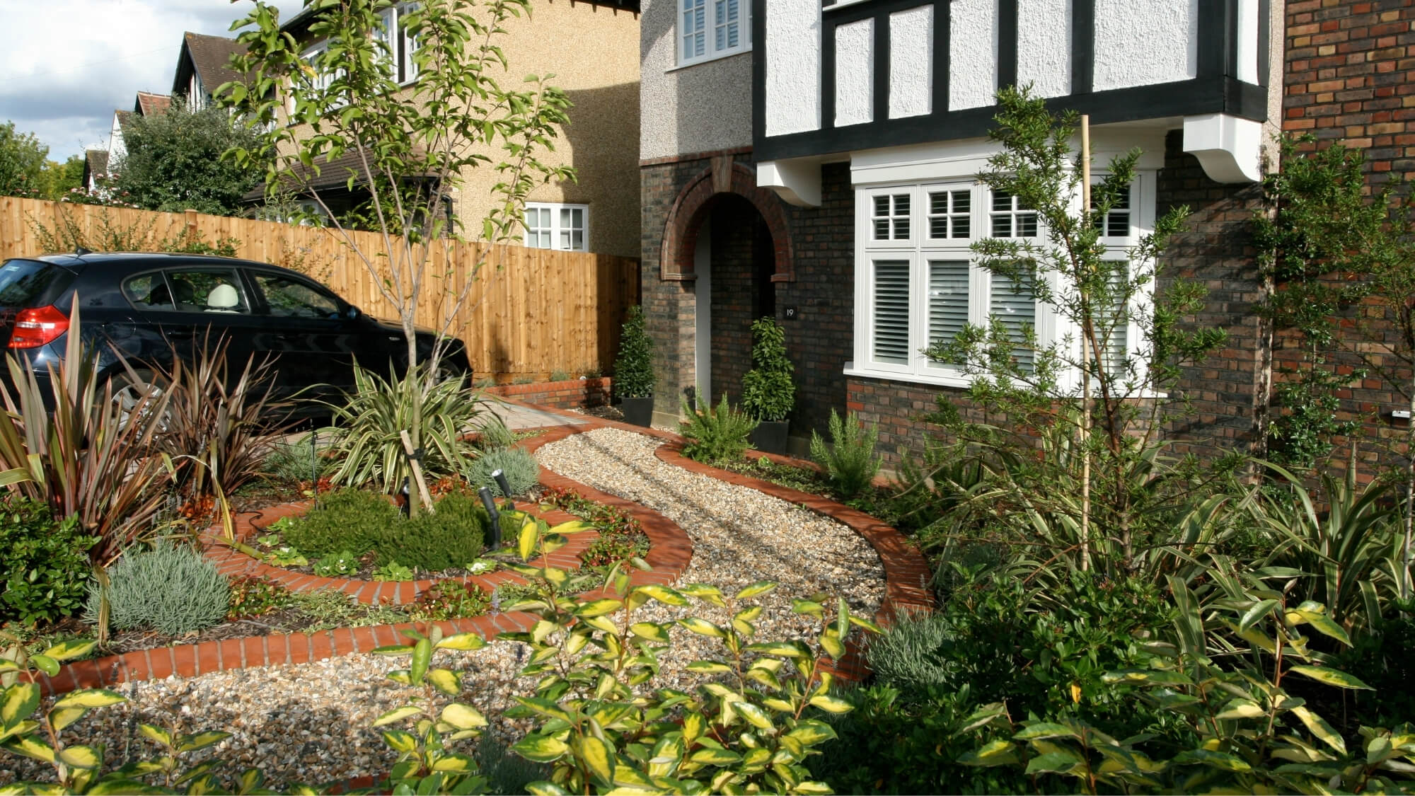 Front garden design with driveway, curved gravel path and lush planting in South London