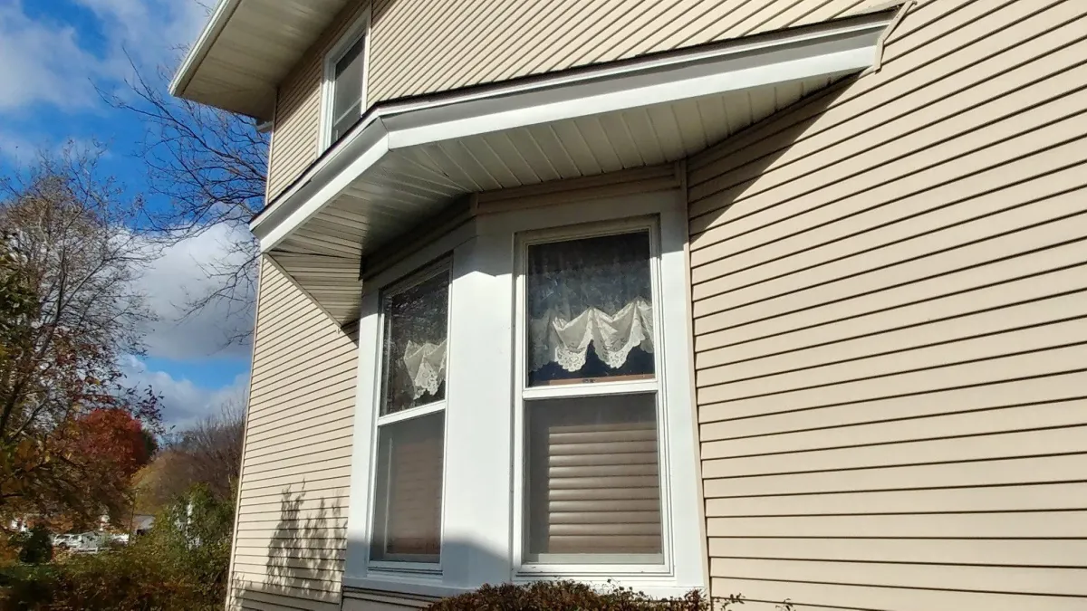 House exterior with tan vinyl siding and white-framed windows.