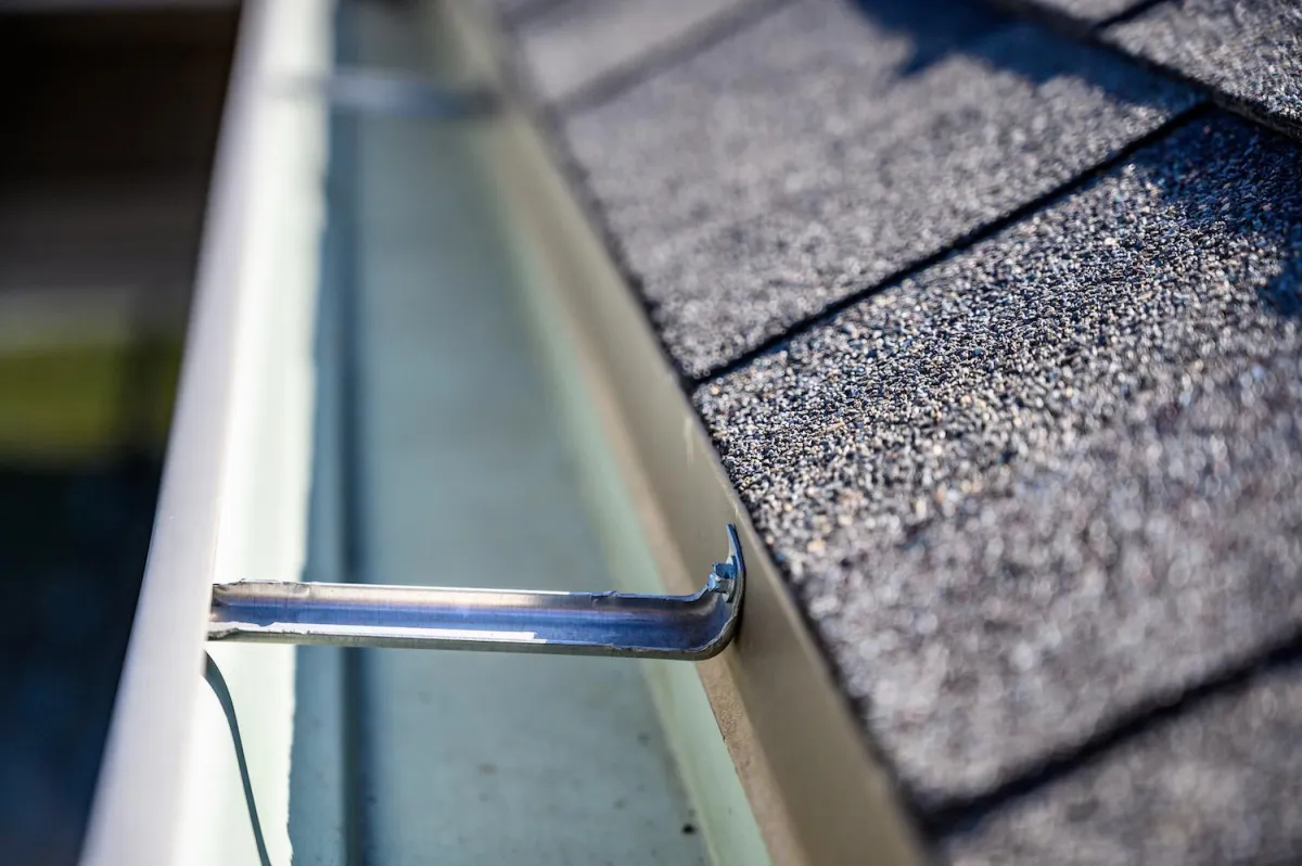 Close-up of roof shingles and gutter system installation.
