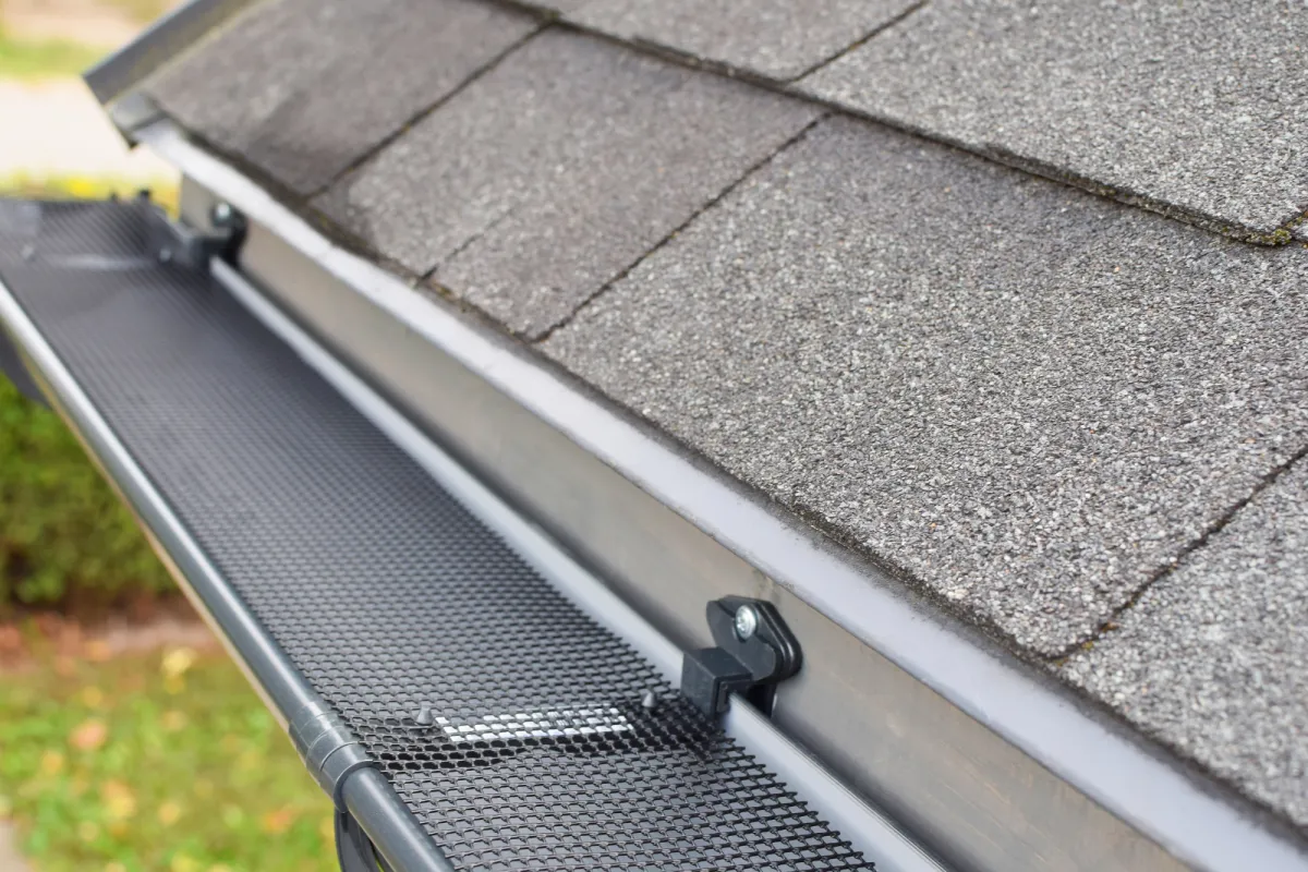 Close-up view of a house roof with a seamless aluminum gutter and mesh guard for water drainage protection.