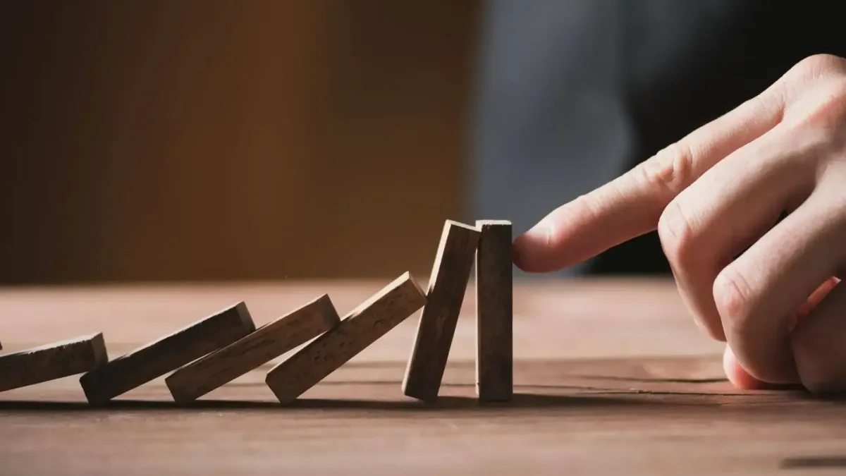 Main stoppant la chute de dominos, représentant la gestion des risques et la flexibilité apportée par un bon financement.