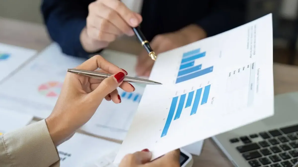 Main pointant des graphiques financiers lors d’une analyse de profil investisseur en gestion de patrimoine.