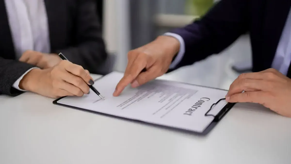 Deux personnes signant un contrat immobilier, représentant la négociation des conditions de vente ou de location.