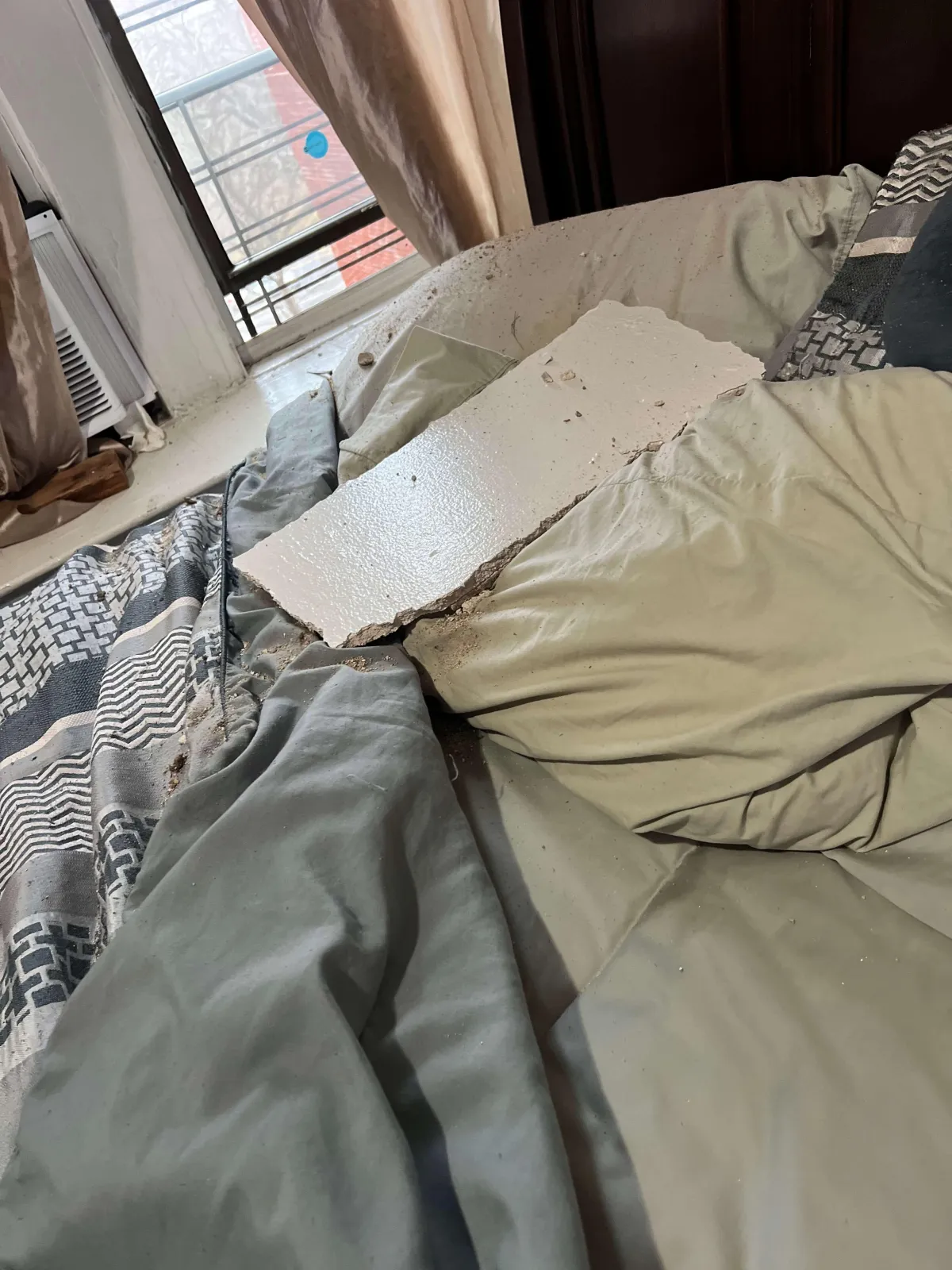 A large piece of fallen ceiling debris on a bed in a Bronx apartment, highlighting hazardous living conditions and potential personal injury claims. If you’ve been injured in a ceiling collapse accident, our Bronx personal injury lawyers can help