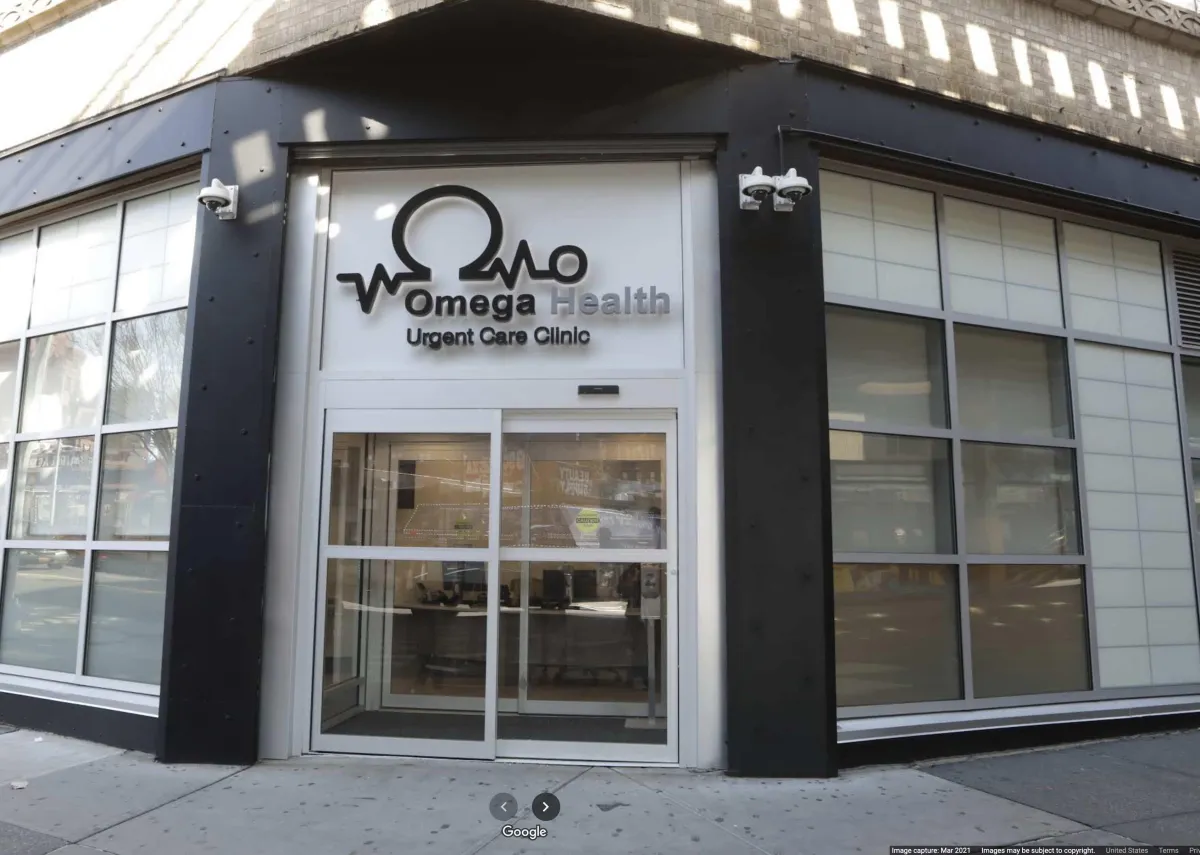 Front entrance of Omega Health Urgent Care at 1 West Burnside Avenue, showing glass doors and signage.