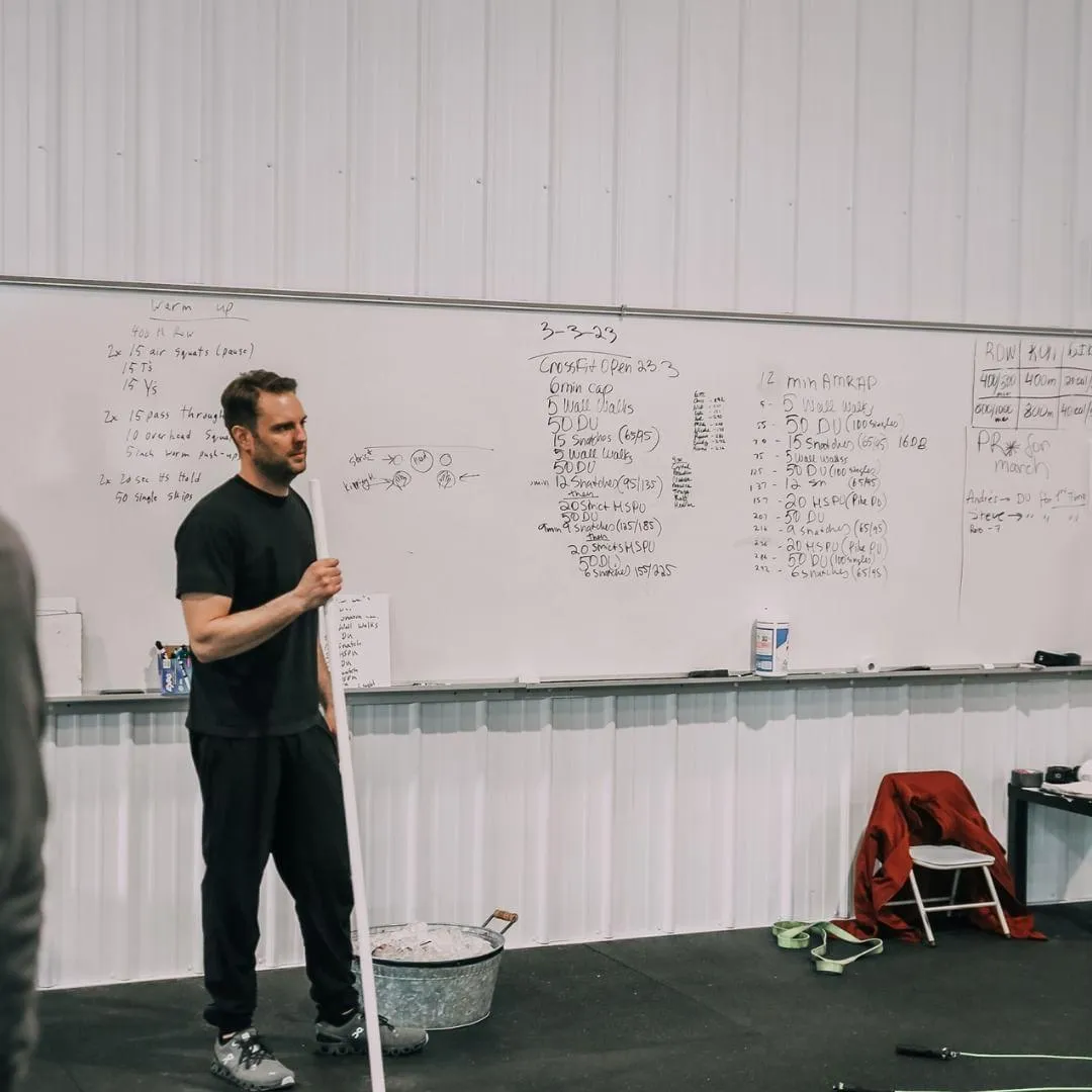 A group of diverse, happy members smiling and high-fiving each other after completing a challenging workout. The atmosphere is energetic and supportive, showcasing the community spirit of CrossFit Shelby