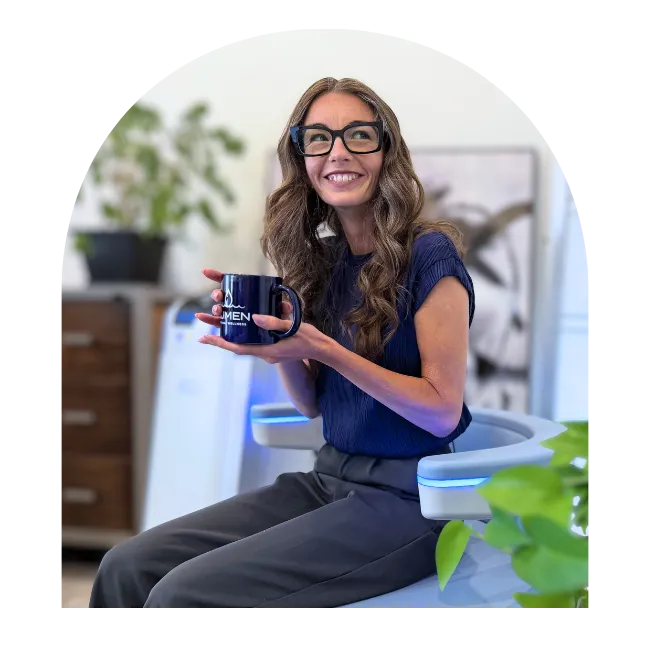 Woman smiling on Emsella chair with coffee
