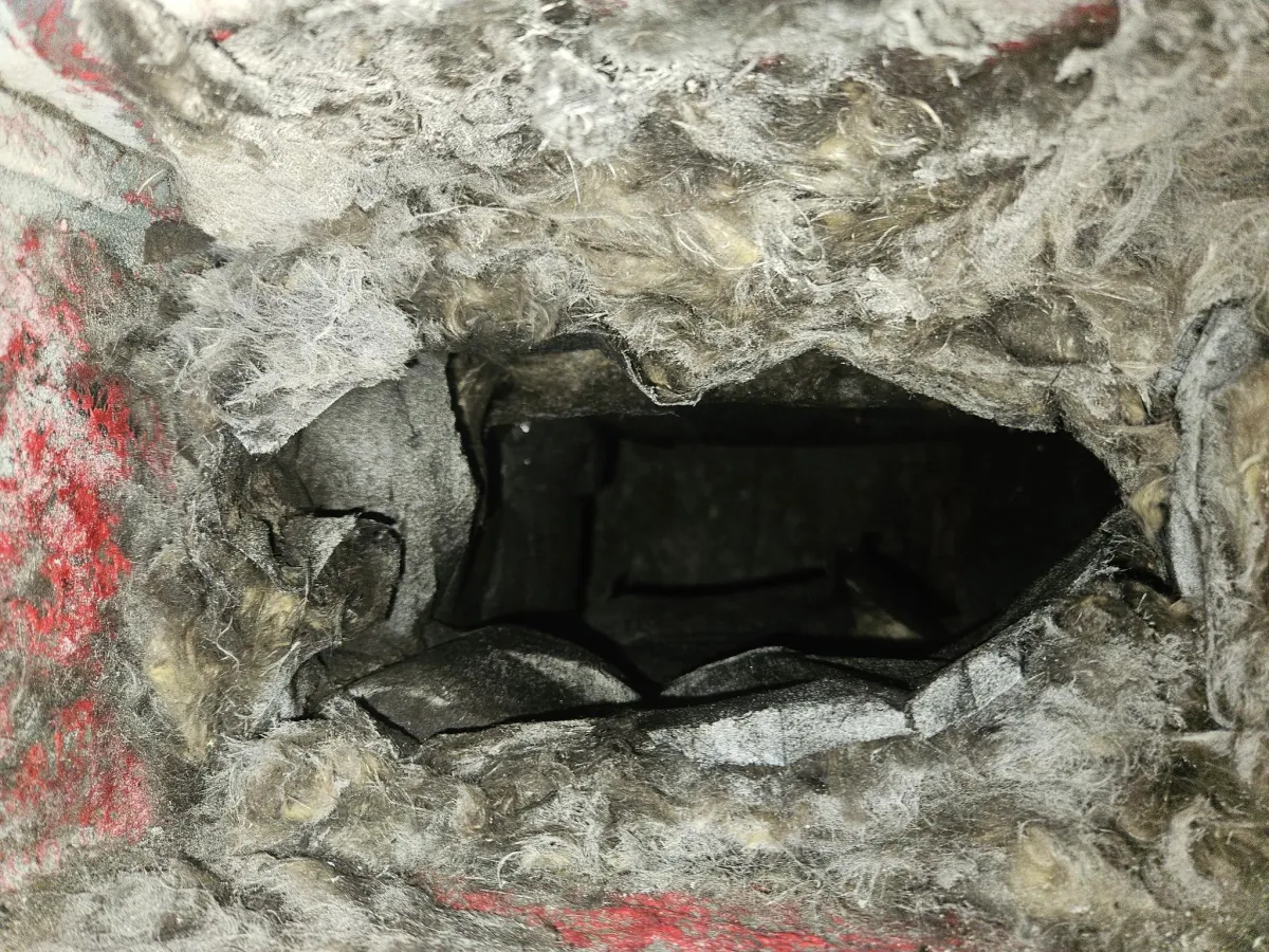 Severely deteriorated ductboard HVAC duct showing air leakage and insulation breakdown