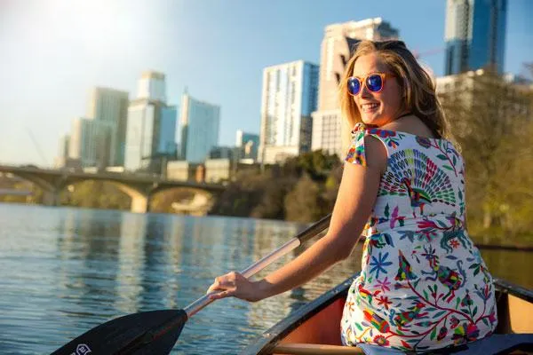 local woman rowing in a boat with city in background