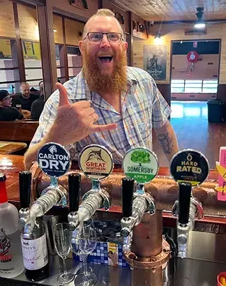 A man posing playfully at the saloon bar.