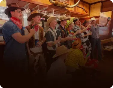 A group of men in cowboy hats and western costumes celebrating a party at the bowling alley.