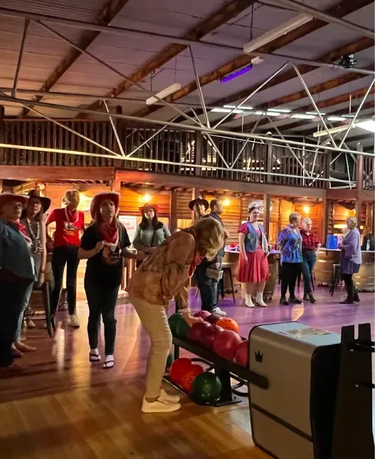 People wearing cowboy hats and western attire enjoying a night at the Wild West Bowling alley.