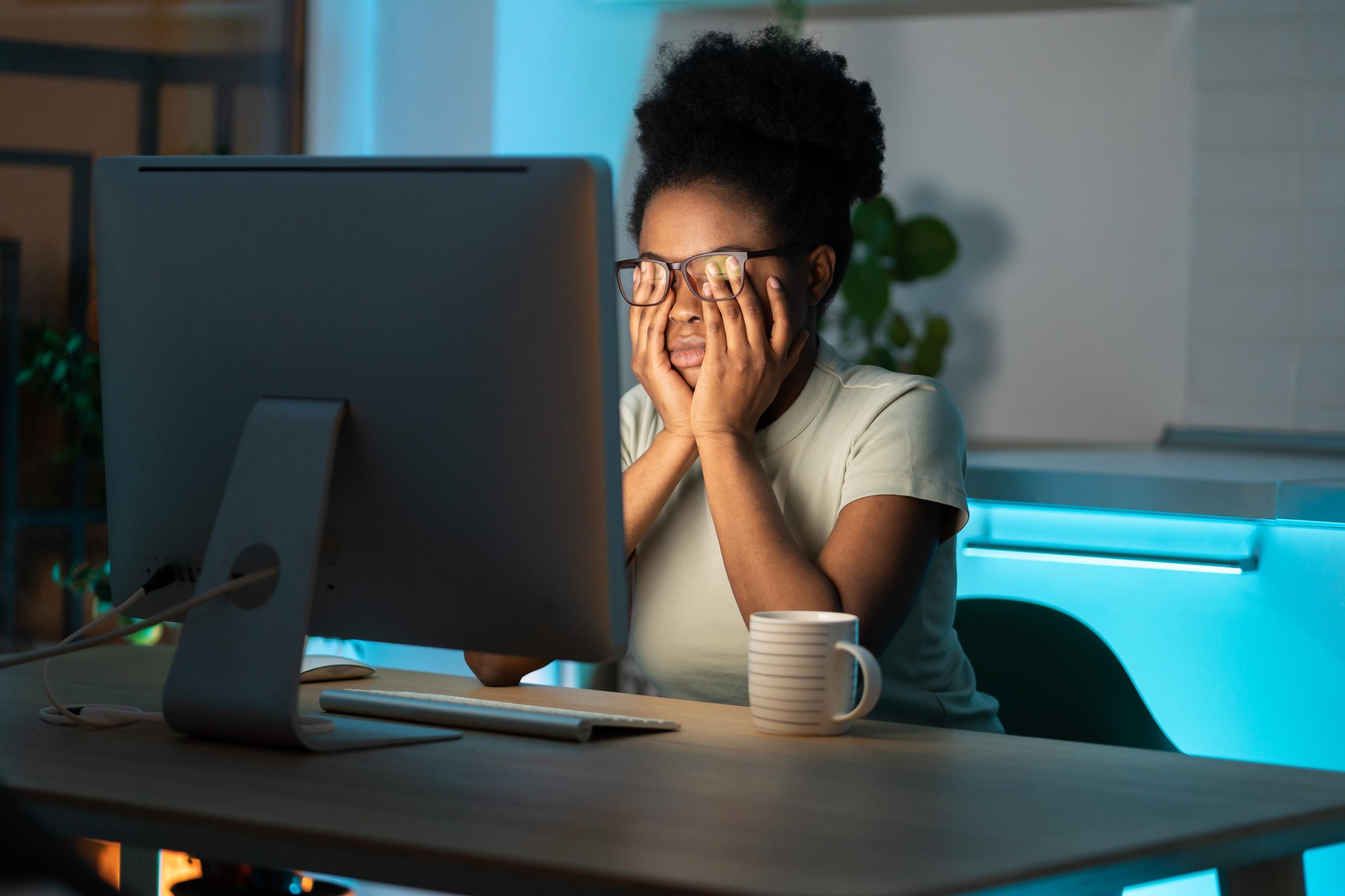Female entrepreneur suffering through burnout at the computer in the dark.
