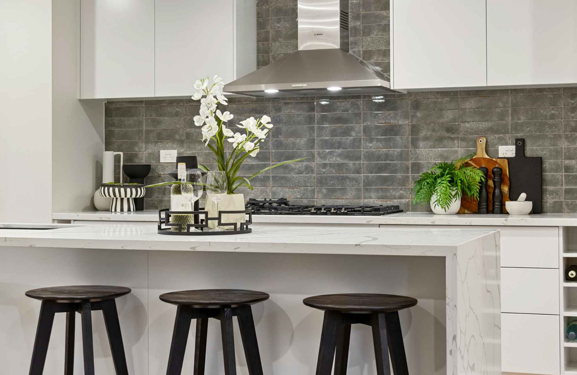 straighten-up-homes-manhattan-beach-ca-spring-home-edit-kitchen-with-waterfall-island-vase-of-flowers-on-island-white-cabinets-styled-home