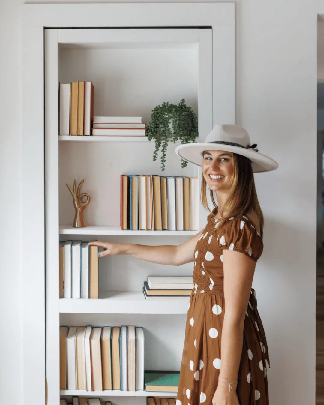 Ashley smiling in front of a bookshelf for straighten up homes