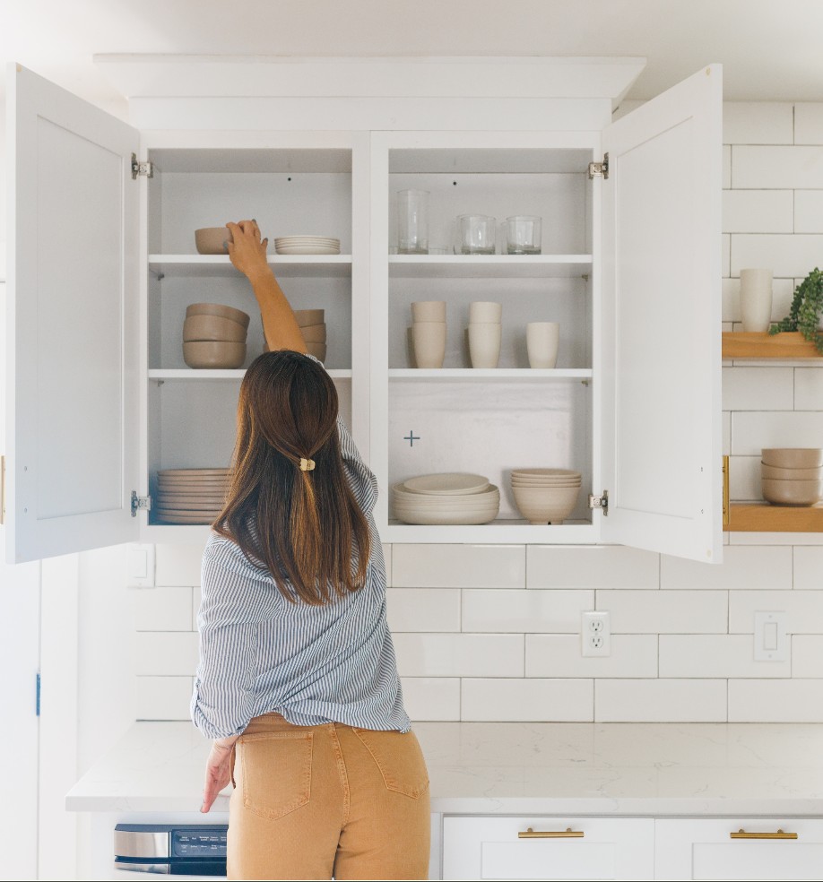 Ashley from Straighten Up Homes putting dishes into kitchen cabinet