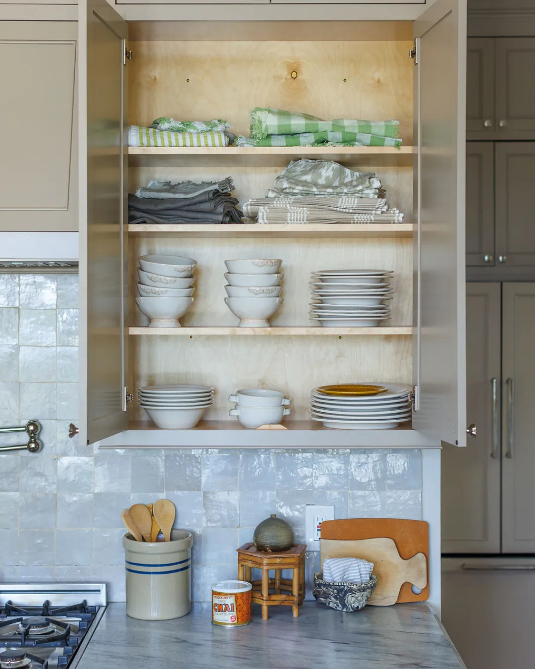 Ashley from Straighten Up Homes putting dishes into kitchen cabinet