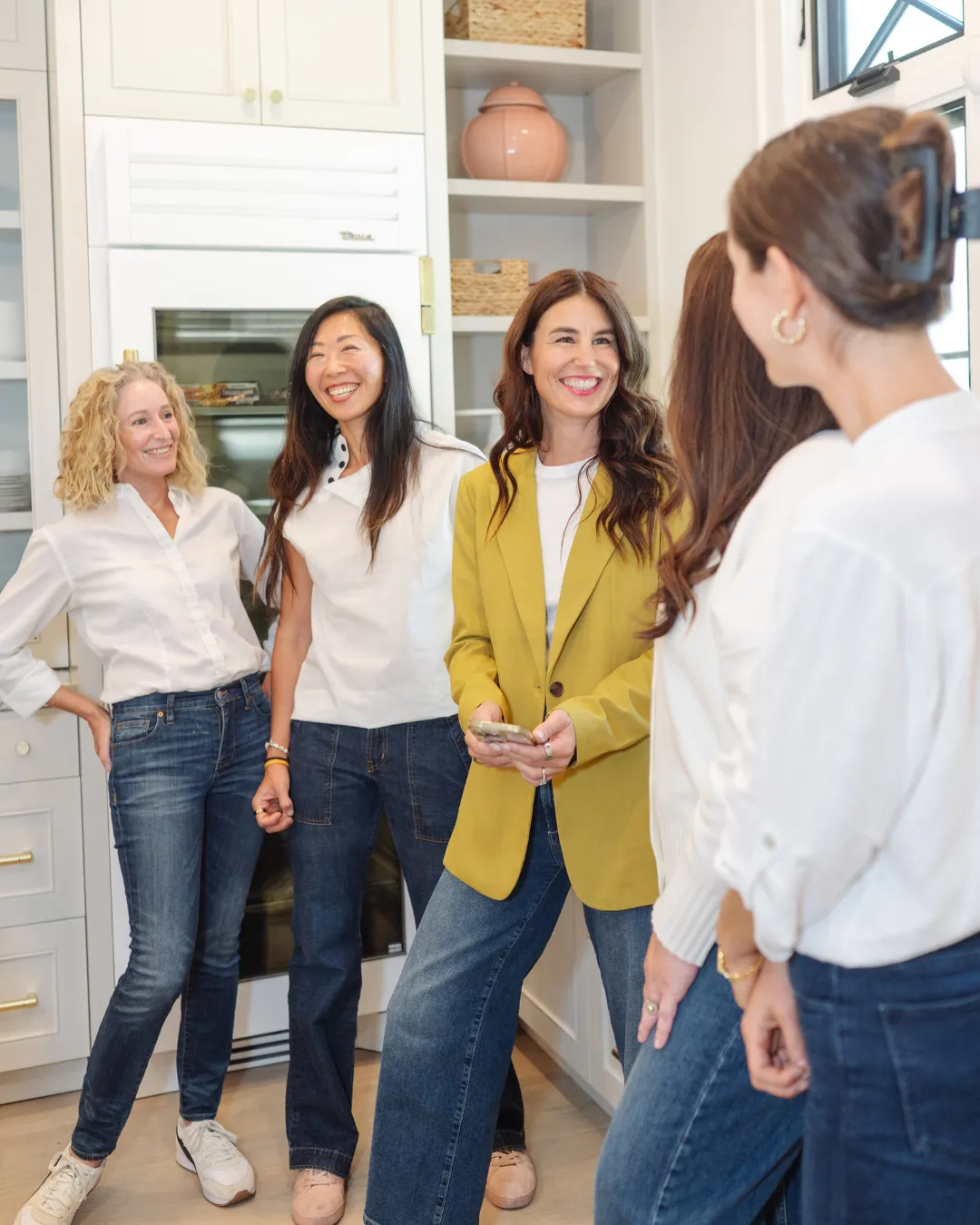 Kaymenity Home founder Ashley laughing with her organizing team in a white kitchen