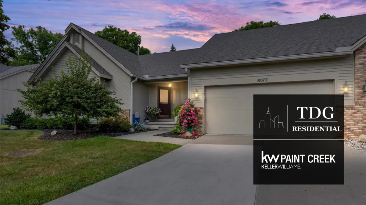 Grand Blanc condo for sale at 8077 Sawgrass Trail with a vaulted exposed-beam great room, wooded backyard, west-facing deck, and main-floor living, listed by The Delia Group.
