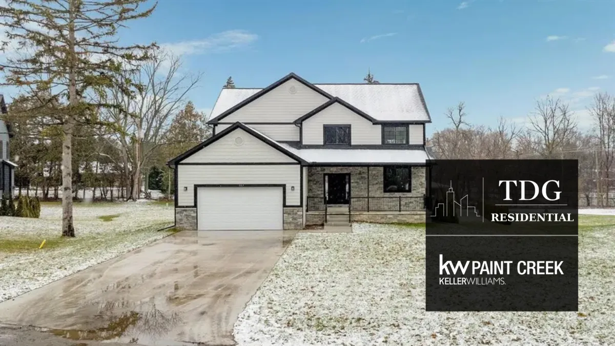 Architectural Bloomfield Hills home with dramatic rooflines, a stone-accented facade, private deck, mature landscaping, and walk-out basement.