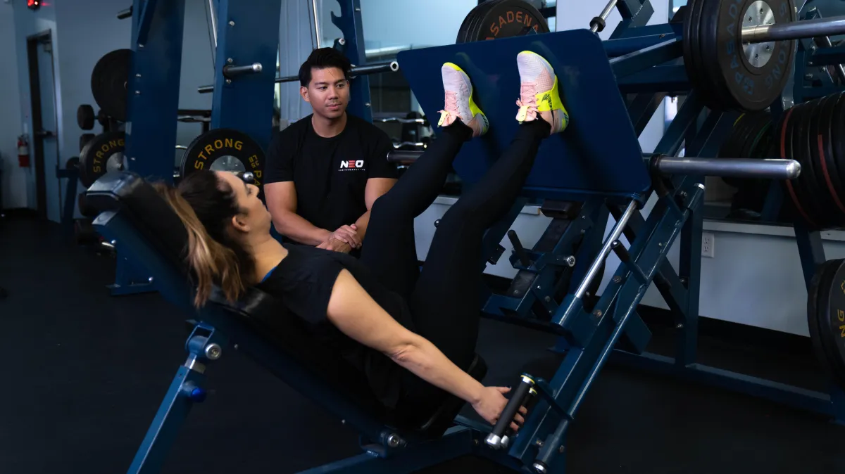 Female personal training client performing a leg press exercise in a gym