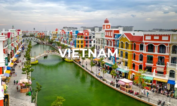 Colorful riverside street in Vietnam with pastel buildings, a canal, and people walking along the promenade.