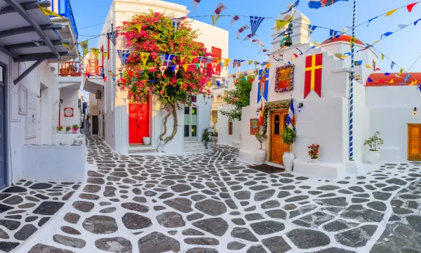 Charming cobbled street in Mykonos, Greece with vibrant flags
