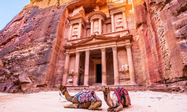 Ancient carved facade of Petra in Jordan with camels resting in front – a must-see UNESCO site on Middle East cruises.