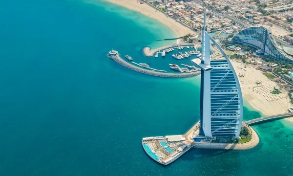 Aerial view of the iconic Burj Al Arab 7-star hotel in Dubai, surrounded by turquoise waters and luxury yachts – symbolizing elite service and Middle East luxury.