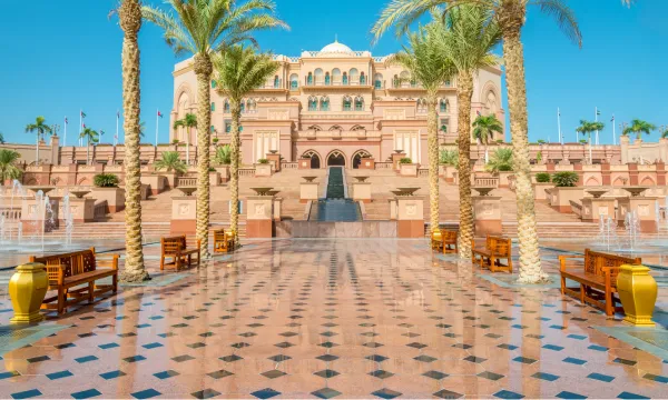 Opulent view of the Emirates Palace in Abu Dhabi, framed by palm trees and golden fountains, showcasing grand Arabian architecture and luxury – a hallmark of Middle East cruises with Luxury Sassy Cruises.