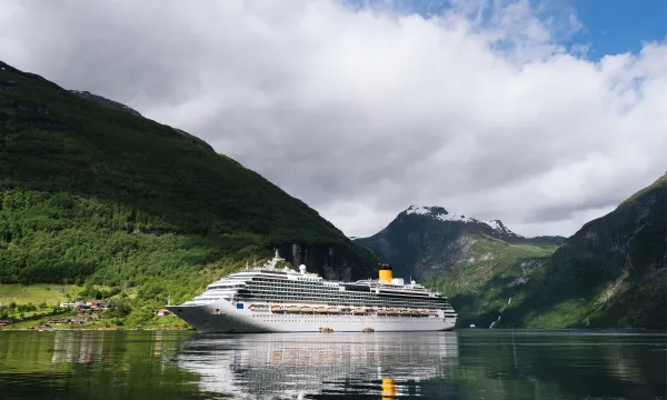 A luxury cruise ship sails through Norway’s Geirangerfjord, surrounded by lush green mountains and snow-capped peaks – a serene and iconic Northern Europe cruise experience.