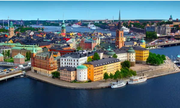 Panoramic view of Stockholm’s Gamla Stan (Old Town), with colorful historic buildings, church spires, and docked boats surrounded by deep blue waters – a vibrant Northern Europe cruise destination.
