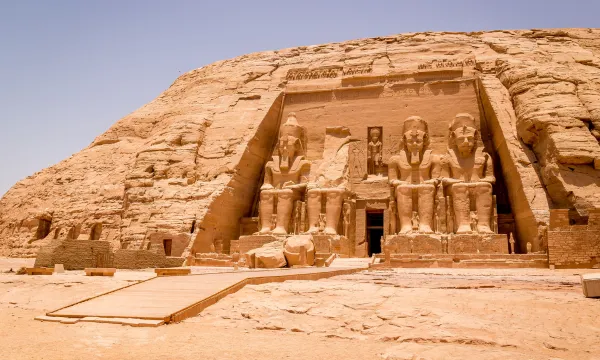 Ancient Abu Simbel Temple in Egypt, featuring massive statues of Pharaoh Ramses II carved into a sandstone cliff under a clear desert sky.