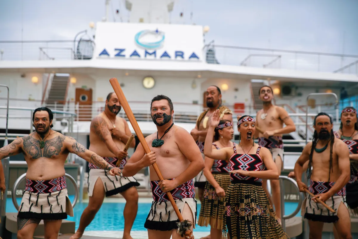 Māori performers in traditional dress delivering a haka welcome ceremony on the pool deck of an Azamara cruise ship.
