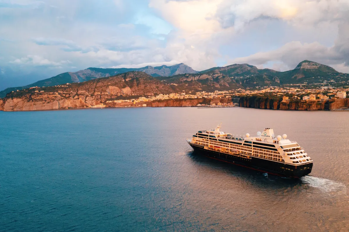 Azamara cruise ship sailing along the Amalfi Coast near Sorrento, Italy at sunset.